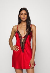 Red satin nightdress featuring a deep V neckline with black lace trim and detailing, adjustable straps, and a relaxed fit.