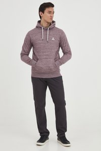 Sudadera burdeos con un patrón texturizado, capucha con cordón y bolsillos frontales, combinada con pantalones oscuros y zapatillas negras.