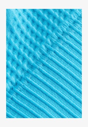 Tejido de color azul claro con textura que presenta nervaduras elevadas y un acabado aterciopelado, creando una superficie suave y táctil.