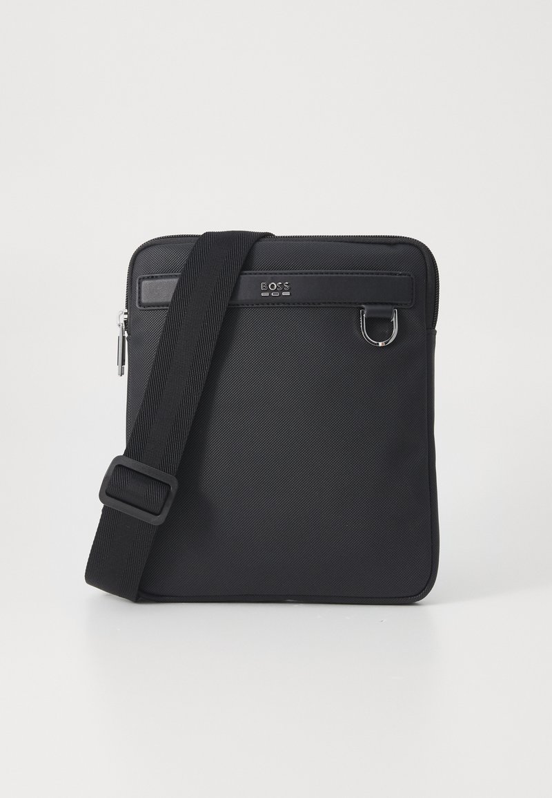 Black textile messenger bag with adjustable strap, zipper closure, front pocket, branded detail, and silver hardware accents.