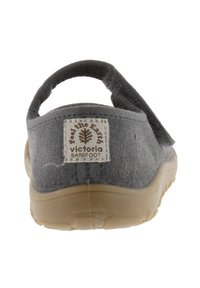 Zapato de ante gris tipo slip-on con una suave correa trasera, suela de goma color beige y una etiqueta de marca "Feel the Earth" en el talón.