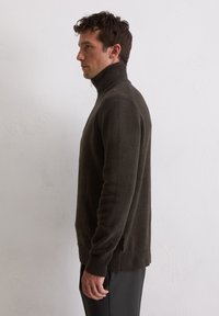 Dunkelbrauner, gestrickter Rollkragenpullover mit gerippten Bündchen und Saum, der eine schlanke Passform und strukturierten Stoff aufweist. Die Seitenansicht zeigt einen hohen Kragen.