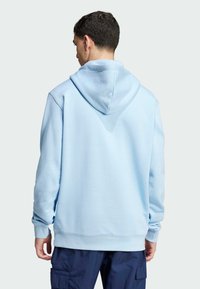 Felpa azzurra in tessuto morbido e texturizzato, con un grande cappuccio, vestibilità rilassata e polsini a costine, abbinata a pantaloni cargo blu navy.