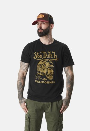 T-shirt noir avec imprimé graphique doré d'un casque vintage et texte "Von Dutch California." Coupe décontractée, avec des manches courtes et un col rond.