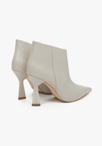 Jasnoszare botki za kostkę wykonane z gładkiej skóry. Posiadają spiczasty nosek oraz unikalny, kanciasty obcas. Minimalne detale przeszycia po bokach.