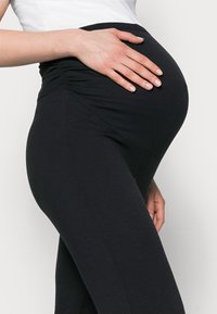 Melni grūtniecības legingi ar mīkstu, elastīgu audumu, ar plašu, savākto jostu, kas paredzēta, lai pielāgotos augošam vēderam.