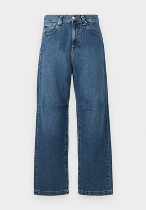 Kék farmernadrág laza szabással, egyenes lábakkal, látható varrással és elülső gombos zárással. Oldalsó zsebvel rendelkezik, amely kiemeli a dizájnt.