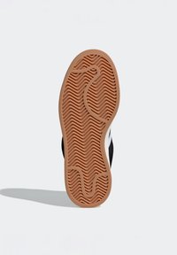 Crna guma potplate tenisica s teksturiranim uzorkom. Ima bež međupotplat i istaknute zakrivljene utore za prianjanje.