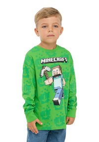 T-shirt verde a maniche lunghe con grafica di un personaggio di Minecraft. Il materiale è cotone morbido con un design pixelato e polsini a coste.