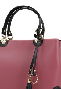 Roze handtas met zwarte leren afwerking en gouden beslag. Voorzien van dubbele handvatten, verstelbare riem en een gladde, matte textuur.