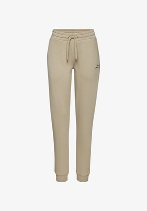 Beige Jogginghose mit elastischem Bund, Kordelzug, Bündchen an den Knöcheln und kleinem Textdetail am rechten Oberschenkel.