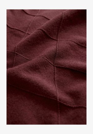 Burgundy stickad tyg med ett strukturerat diamantmönster, med synliga sömnadsdetaljer och mjuk, slät yta.