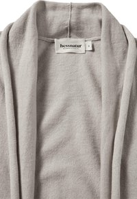 Lichtgrijze cardigan van zacht, geweven materiaal. Voorzien van een sjaalkraag en het merklabel "hessnatur" aan de binnenkant.
