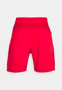 Shorts de sport rouges avec une taille élastique, un tissu lisse et une poche latérale zippée. Design simple et longueur au-dessus du genou.