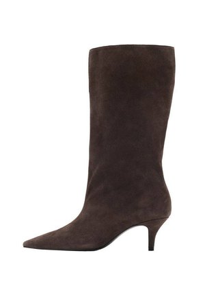 Stivale in suede marrone, con punta affusolata e tacco medio, caratterizzato da una texture liscia e un design elegante.