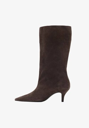 Botă din suede maro, până la genunchi, cu vârf ascuțit și toc mediu, având o textură netedă și un design elegant.