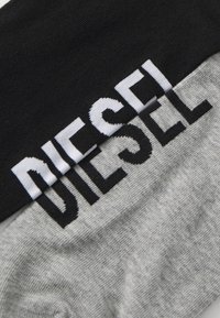 Szürke és fekete zoknik, a fekete passzéba fehérrel kötött "DIESEL" logóval. Simító felület, standard zokni forma.