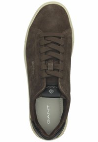 Braune Wildleder-Sneaker mit Schnürdesign, cremefarbener Gummisohle und schwarzem Fersenakzent. Logo auf der Zunge sichtbar. Glatte Innenauskleidung.