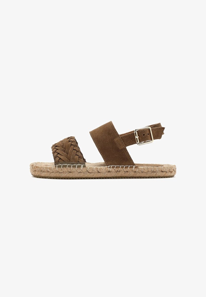 Brown suede sandal with braided toe strap, wide ankle strap, and adjustable metallic buckle. Jute-wrapped sole for added texture.