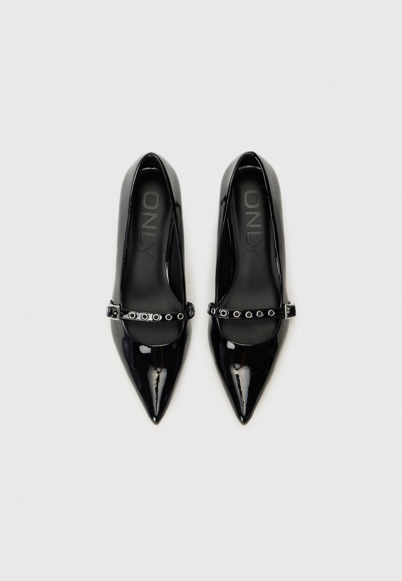 Tacones altos de charol negro con punta afilada, correa en el tobillo con ojales metálicos y un acabado suave y brillante.