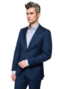 Granatowy garnitur w kratę z dwoma guzikami, połączony z jasnoniebieską koszulą w białe paski. Gładki materiał i dopasowany krój.