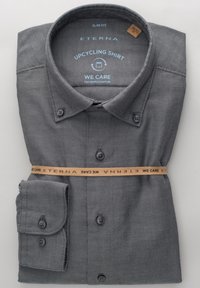 Chemise grise upcyclée à coupe ajustée, en tissu texturé. Dotée d'un col boutonné, de deux boutons aux poignets, et sécurisée par une bande de marque.