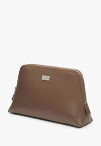 Hnědá kožená taštička se zipovým uzávěrem, vybavená stříbrnou značkovou destičkou, šikmým designem a hladkým povrchem. Vhodná pro různé účely.