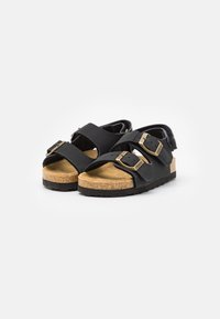Sorte sandaler med doble låser, korksåle og teksturert svart yttersåle. Åpen design med myke stropper for komfort og støtte.