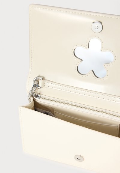 Pung i cremefarve med glat tekstur, der har en sølv lynlåslomme og et udskåret blomster-spejldetalje indeni.