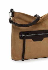 Beige Wildleder-Handtasche mit einem dunkelbraunen Lederriemen und einer Vorderreißverschlusstasche mit langem Zugband.