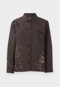 Chemise marron à boutons avec col, ornée de broderies florales et étoilées en or et bleu, et d'une poche sur la poitrine à gauche. En matériau coton.