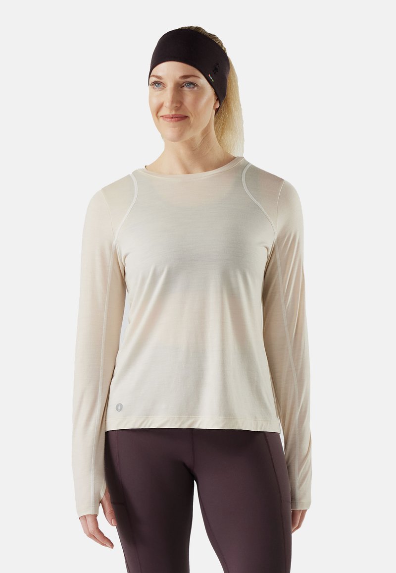 Maglia sportiva a maniche lunghe in tessuto beige chiaro, con maniche raglan e scollatura arrotondata con dettagli di cucitura a contrasto.