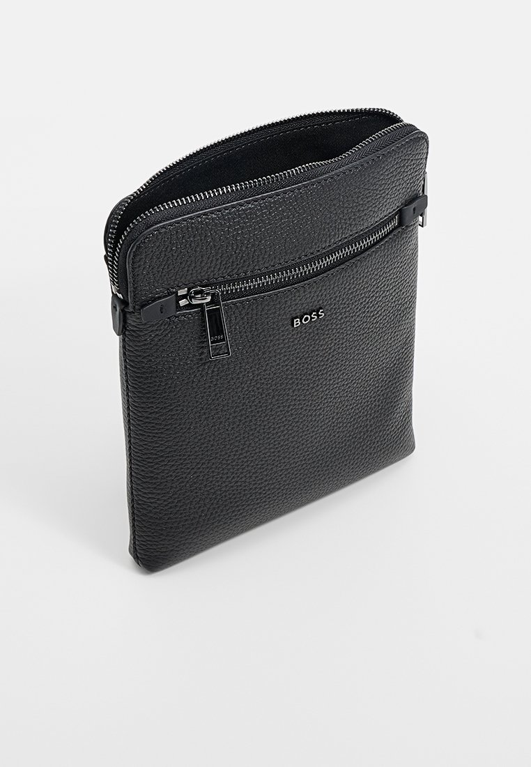 Sac en bandoulière en cuir noir texturé avec poche zippée à l'avant et logo BOSS en argent, compartiment principal partiellement ouvert.