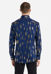 Camisa navy con patrones de flechas metálicas doradas, de manga larga, con puños de botón y un corte entallado. Tejido suave con un cuello clásico y yugo en la espalda.