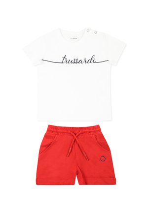 T-shirt bianco con testo "trussardi" nero e bottoni sulle spalle, abbinato a pantaloncini rossi con elastico in vita e tasche laterali.
