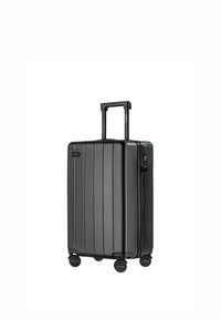 Czarna walizka z twardą obudową, z pionowymi żłobieniami, teleskopową rączką, czterema kółkami i zamkiem błyskawicznym. Gładka faktura i minimalistyczny design.
