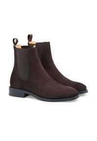 Bottines Chelsea en daim marron avec panneaux élastiques sur les côtés, une languette de tirage et une semelle plate en caoutchouc noir. Texture lisse et design à bout rond.