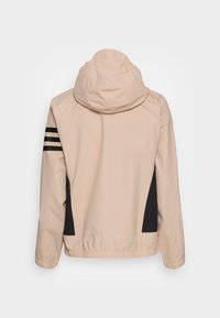 Huva jacka i ljus persikofärg med svarta sidopaneler och tre svarta ränder på vänster ärm. Slät, vattentät tyg.