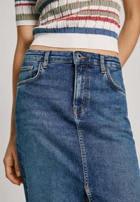 Denim nederdel i mørkeblå, med lige snit, fem-lomme design og lys syning. Mellemhøj talje med knaplukning foran.