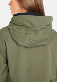 Olivgrüne wasserdichte Jacke mit hohem Kragen und verstellbarem Kapuze, ausgestattet mit glatter Textur und verdeckten Nähten für ein elegantes Erscheinungsbild.