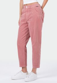 Roze corduroy broek met een hoge taille, twee voorzakken en een toelopend model, gecombineerd met witte sneakers.