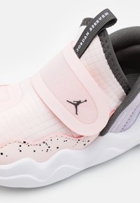 Světle růžové tenisky Jordan 23SEVEN s černým logem Jumpman, černobíle skvrnitou mezipodešví a šedým polstrovaným límcem na bílé podrážce.