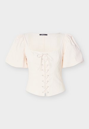 Haut beige clair à manches bouffantes avec un col carré, un devant lacé et des accents à œillets. Confectionné dans un tissu doux et texturé pour le confort.