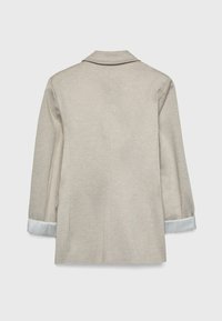 Giacca beige a maniche lunghe con colletto e polsini arrotolati che mostrano una fodera a righe blu e bianche, vista da dietro.