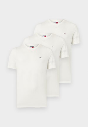 Tri enostavne bele majice kratkih rokavov z okroglim izrezom, zložene ena na drugo, vsaka z majhnim rdeče-bele-modrim pravokotnim logotipom na levi strani prsi.