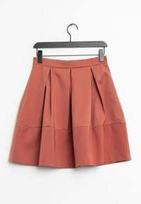 Kleštěná sukně v rezavé barvě, s rozšířenou siluetou, hladkou texturou a čistým pasem, zavěšená na černém ramínku.