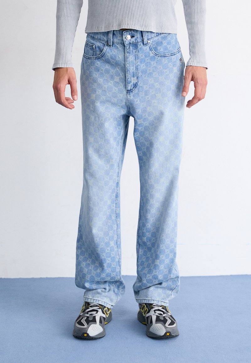 Lyseblå denimjeans med rutemønster, rett bendesign, fem lommer og knappeåpning. Brukt med svarte og gule sneakers.