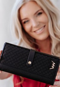 Black wallet with a quilted texture, gold accents, and a logo. Features a flap with a snap closure and a rectangular shape.