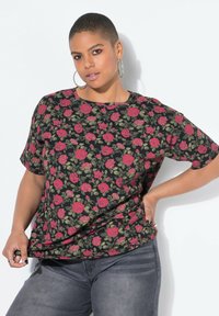 Czarny t-shirt z krótkim rękawem z kwiatowym wzorem przedstawiającym czerwone róże i zielone liście. Miękka tkanina, luźny krój i okrągły dekolt.