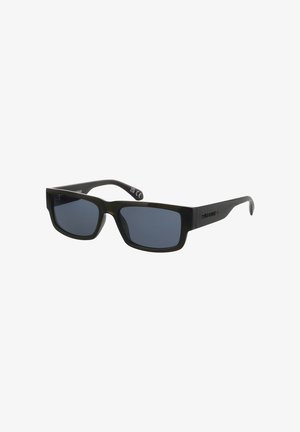 Schwarze rechteckige Sonnenbrille mit dunklen Gläsern und dicken Bügeln, leicht seitlich geneigt vor weißem Hintergrund.